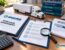 Buying an existing trucking company: buyer and insurance advisor reviewing compliance records beside a full-size semi-truck in a Chicago-area fleet yard branded in Ensure Inc. blue and teal